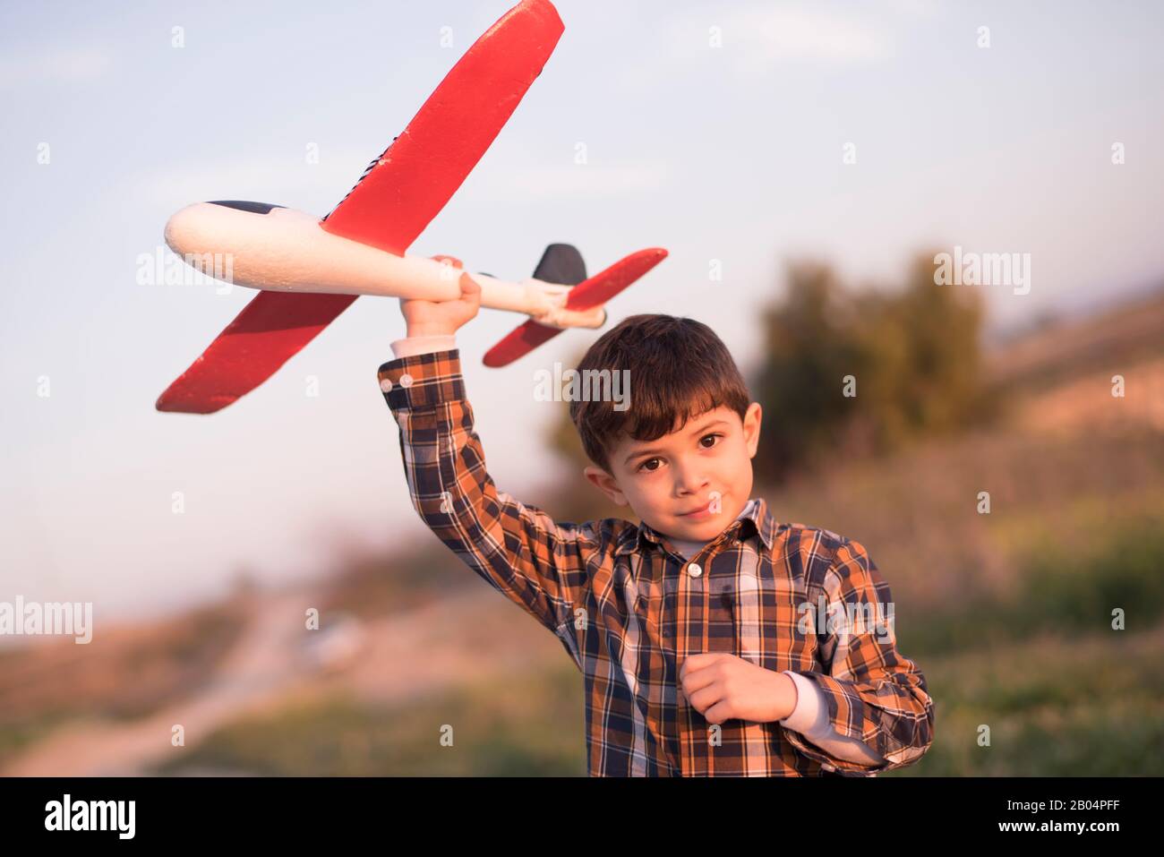 Petit garçon avec un avion jouet jouant au printemps extérieur image Banque D'Images