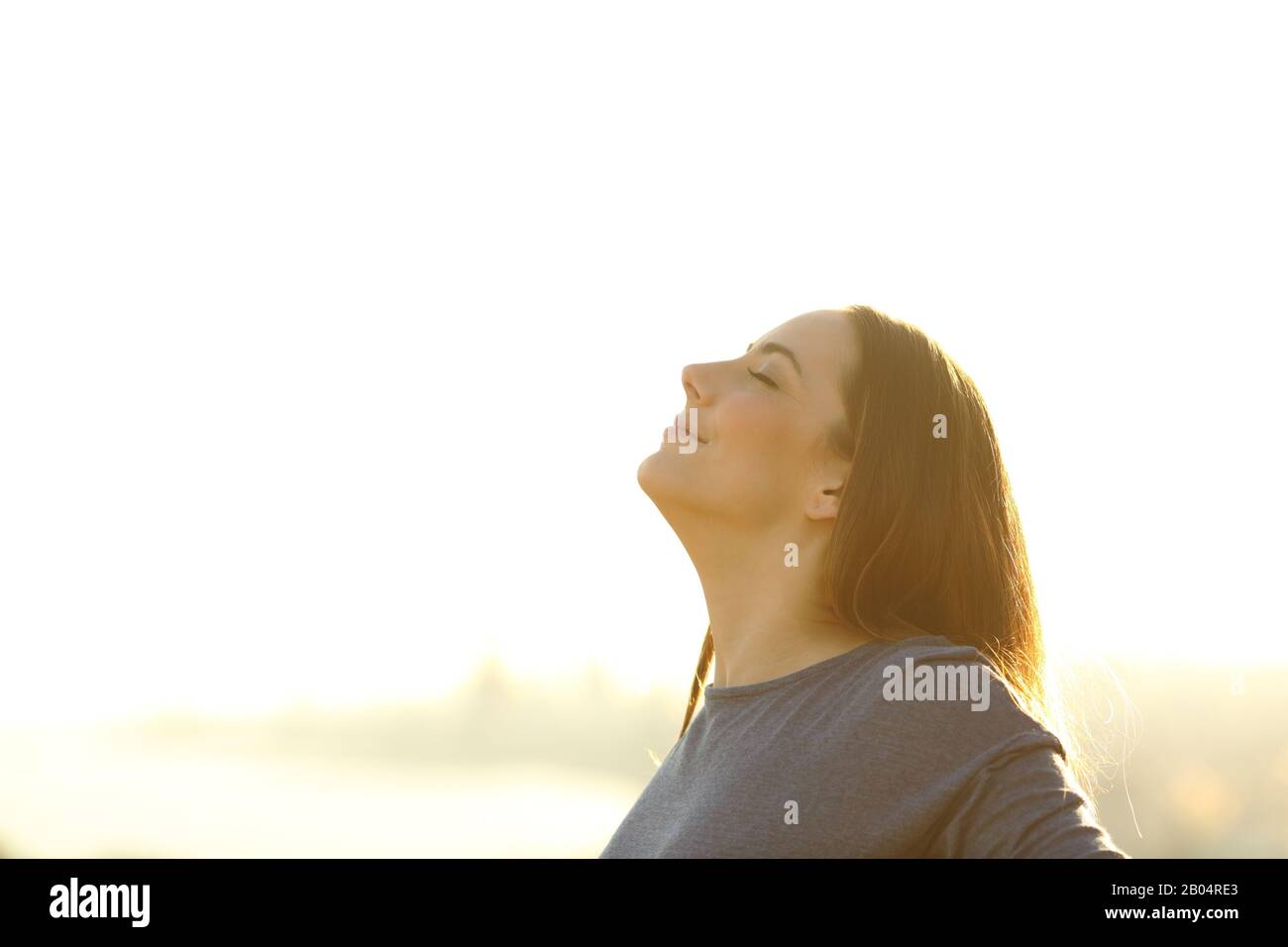 Une femme satisfaite qui respirait de l'air frais à l'extérieur au coucher du soleil Banque D'Images