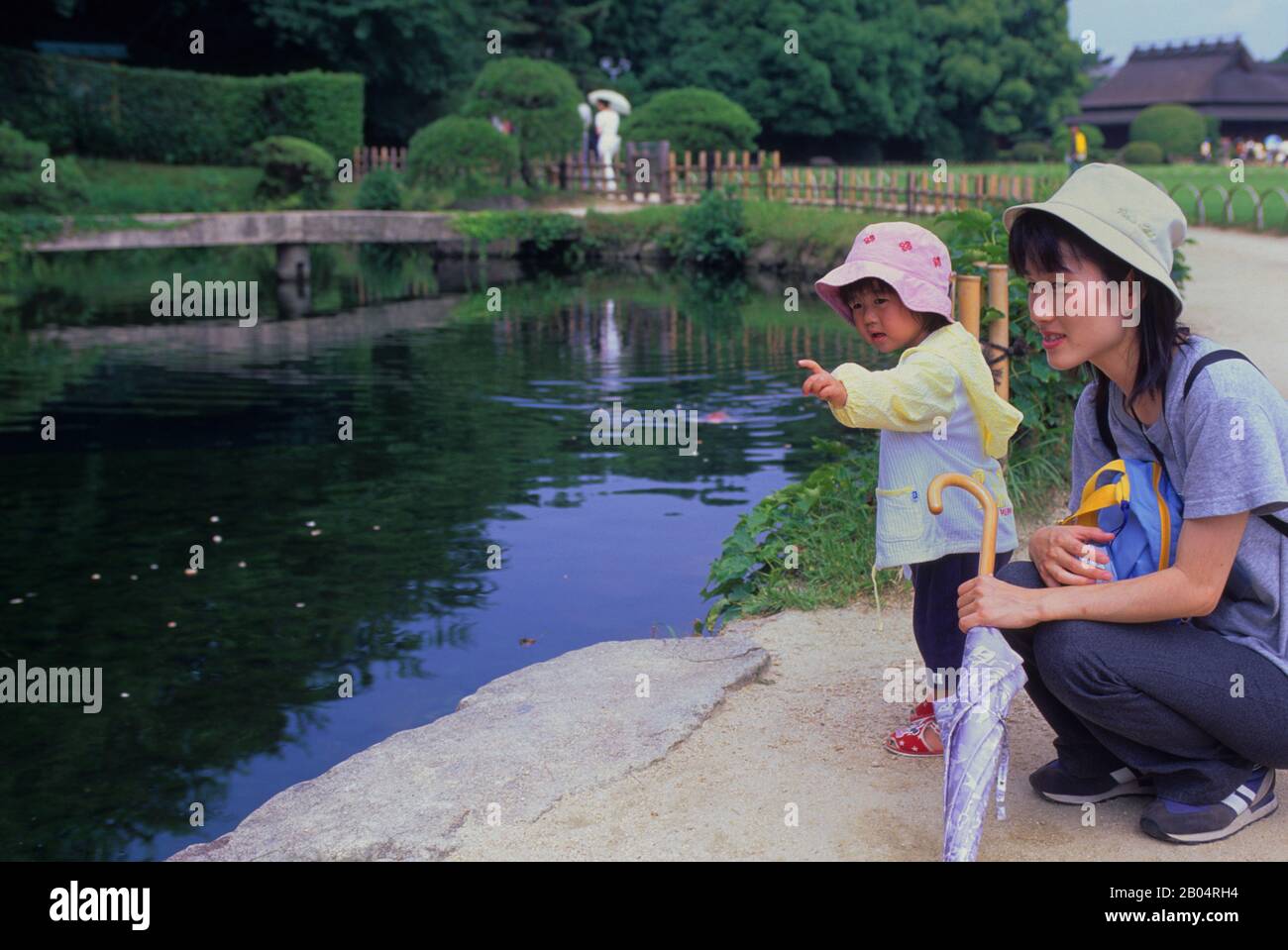 Une mère japonaise avec sa fille à un étang dans le jardin japonais de Korakuen situé à Okayama au Japon. Banque D'Images