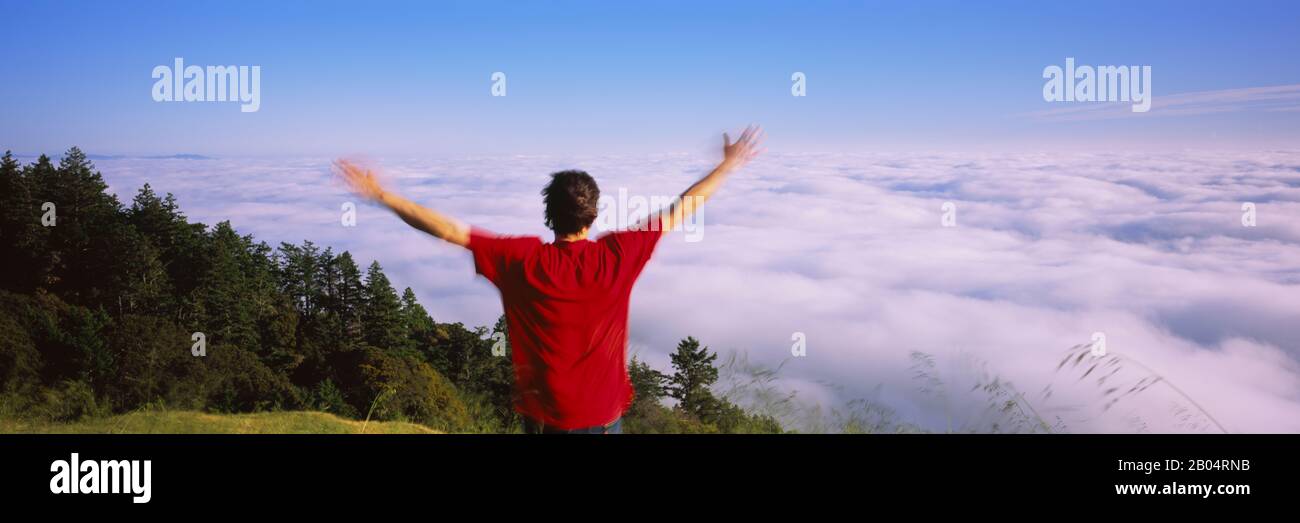 Vue arrière d'un homme debout avec ses bras étirés, Mt Tamalpais, Californie, États-Unis Banque D'Images