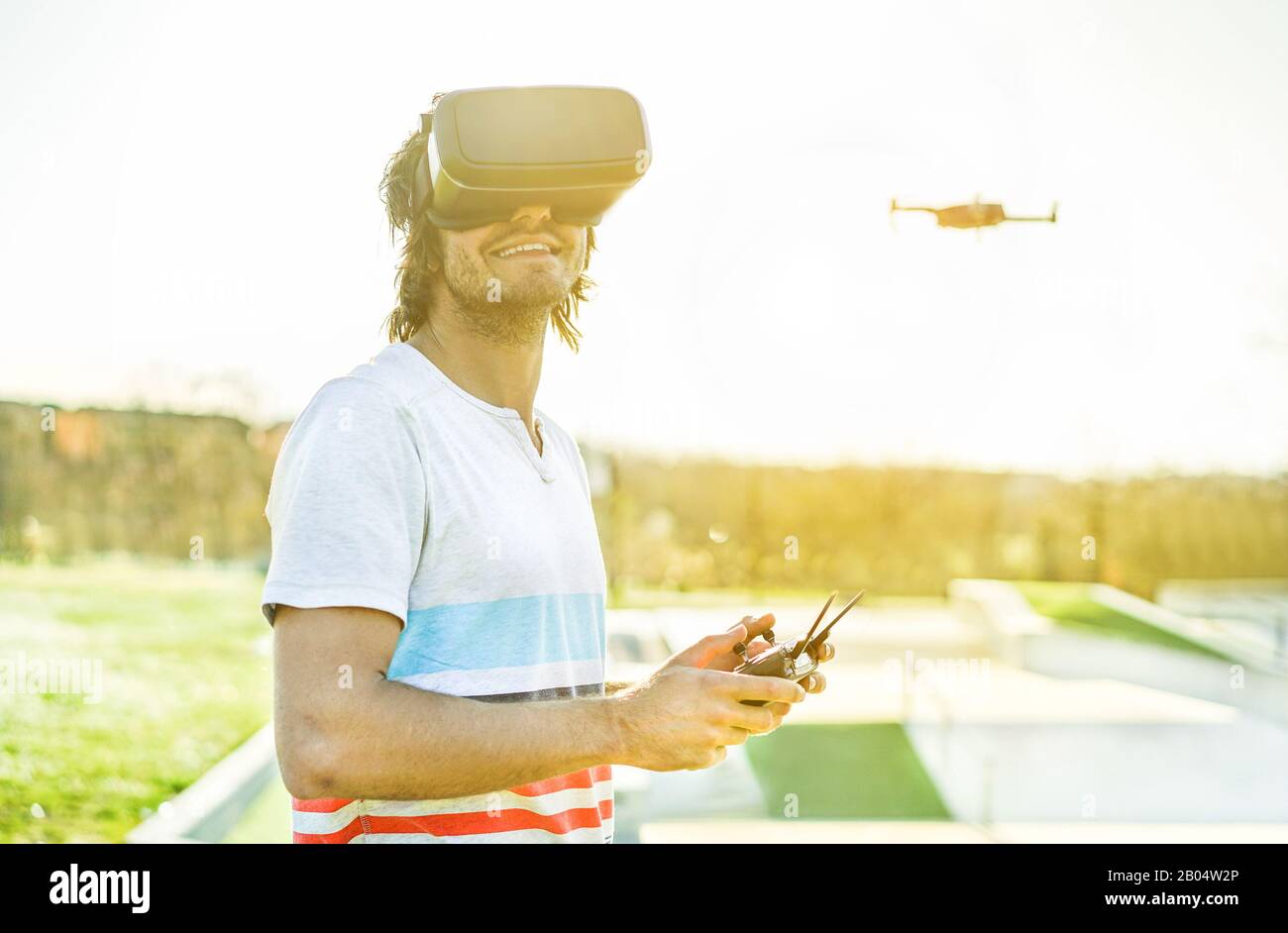 Jeune homme utilisant un drone avec télécommande portant des lunettes de réalité virtuelle faisant des photos et des vidéos - jeune gars s'amuser avec la nouvelle technologie tre Banque D'Images