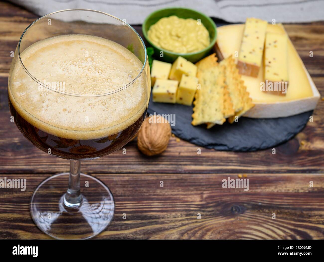 Verser de la bière rouge abbatiale belge en verre et en pierre avec des fromages faits par des moines de lait de vache avec fenugrec et graines de moutarde près Banque D'Images