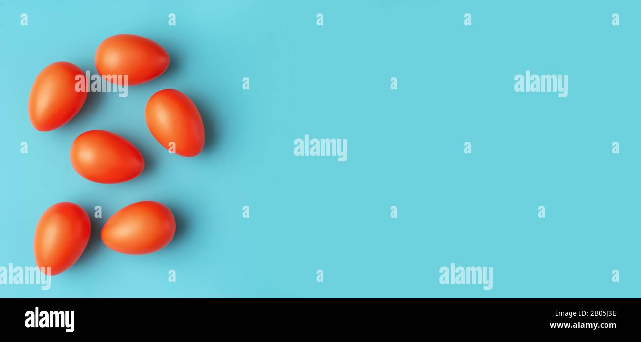 Des œufs de Pâques de couleur rouge et orange à la mode sur fond bleu-vert coloré Banque D'Images