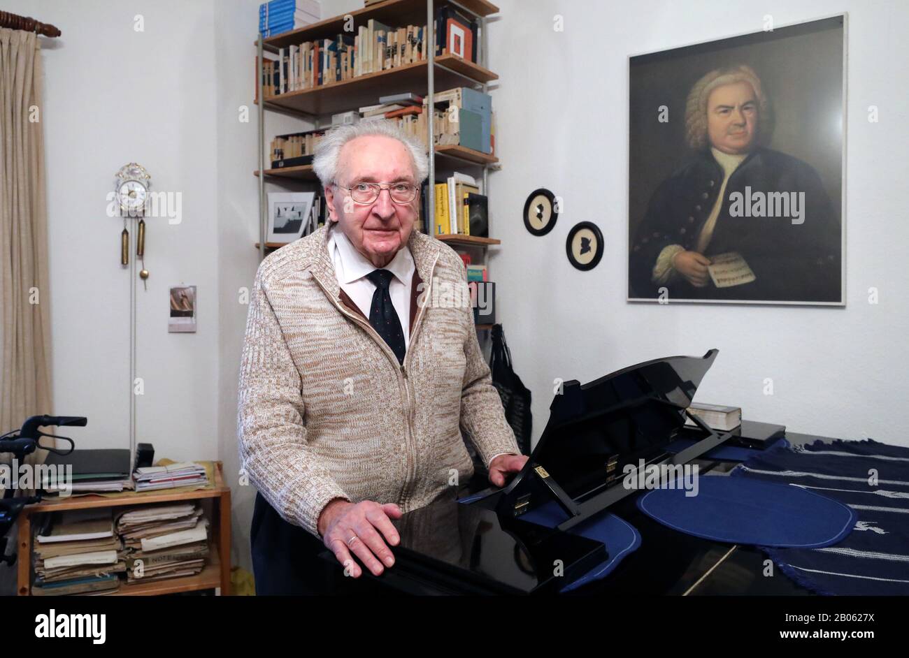 Rostock, Allemagne. 12 février 2020. Hartwig Eschenburg, musicien d'église, se tient à son piano à queue dans son appartement, et un portrait de Johann-Sebastian Bach est suspendu au mur. Le musicien de l'église recevra le Prix social Siemerling de la Fondation Epiphany de Neubrandenburg le 24 février 2020. Le prix est doté de 10 000 euros et est considéré comme le plus ancien prix social du nord-est. Crédit: Bernd Wüstneck/dpa-Zentralbild/ZB/dpa/Alay Live News Banque D'Images