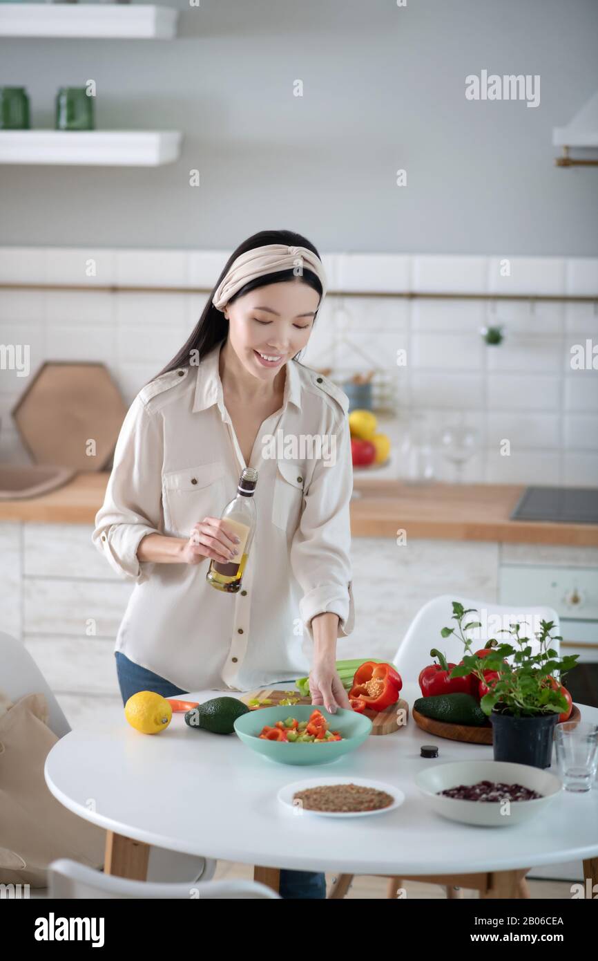 Belle jeune femme avec de l'huile d'olive regardant une salade. Banque D'Images