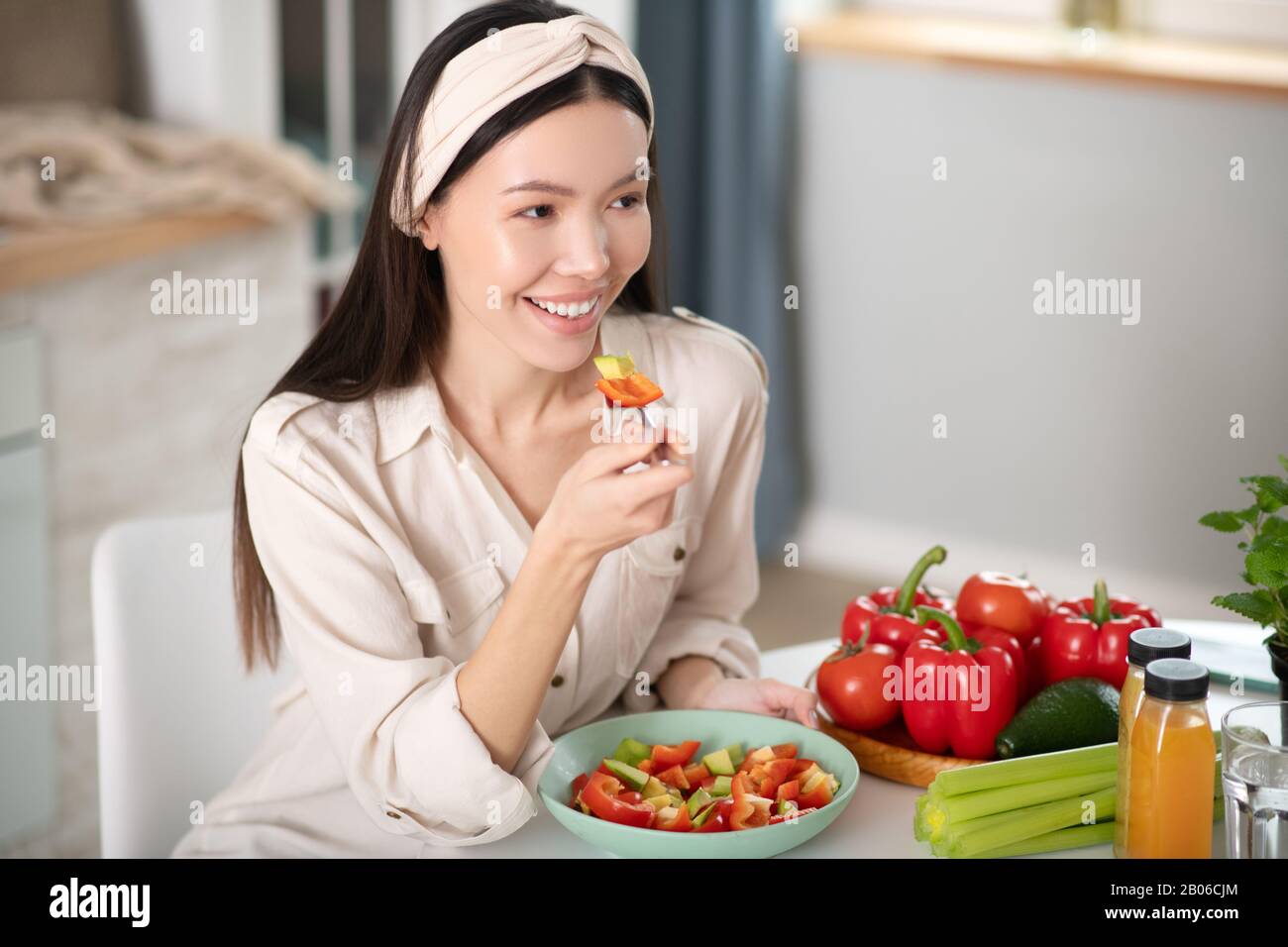 Bonne jeune femme assise à manger de la salade. Banque D'Images