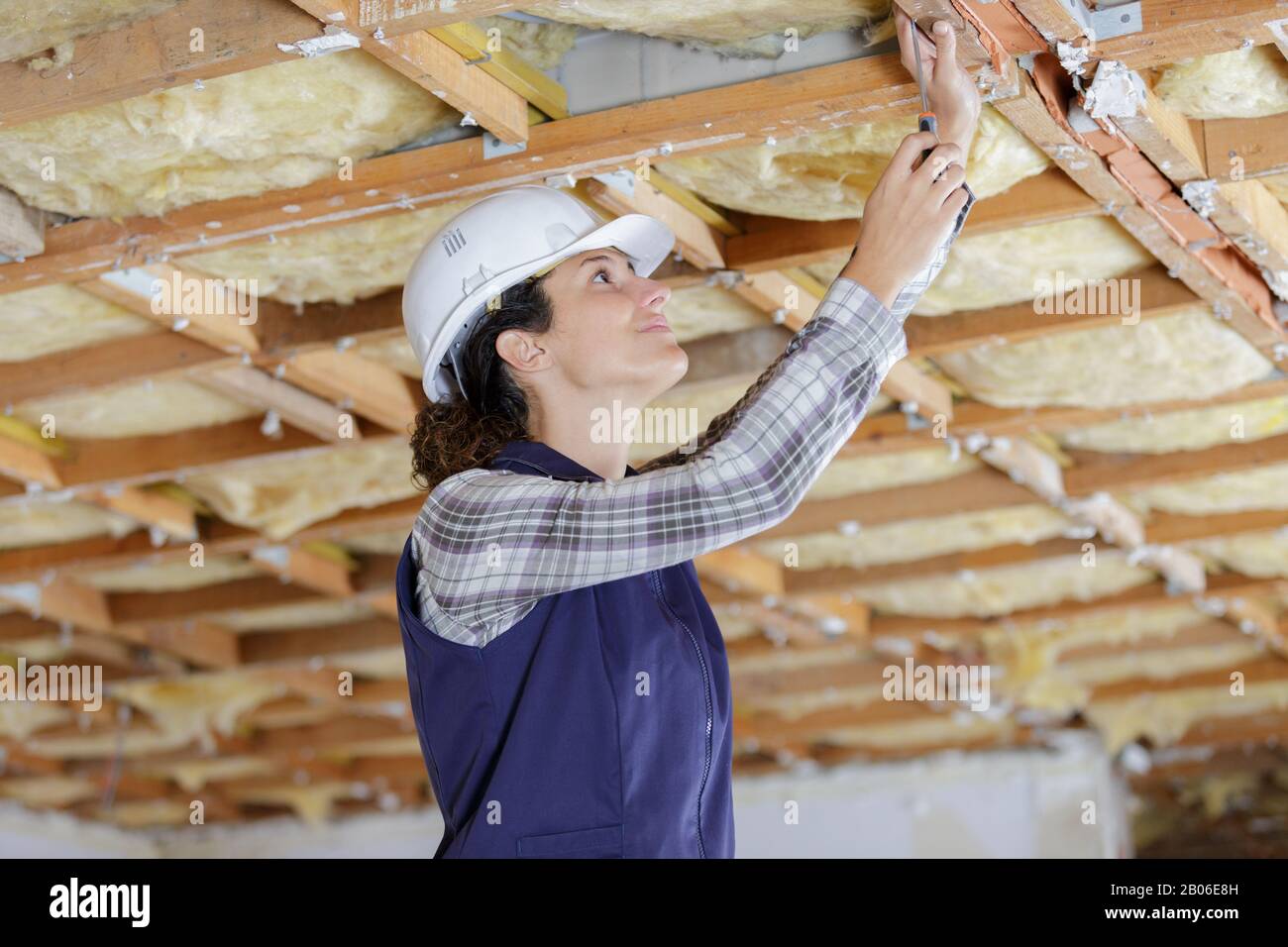 constructeur féminin travaillant sur des supports de plafond en bois Banque D'Images