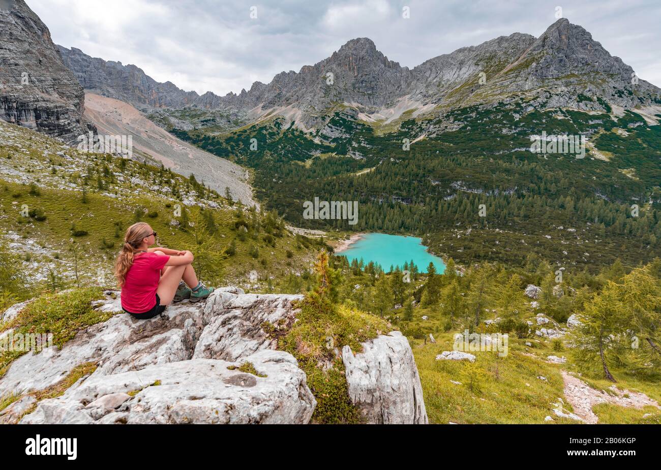 Jeune femme, randonneur assis sur des rochers et regardant le lac turquoise de Sorapeiss et le paysage de montagne, Dolomites, Belluno, Italie Banque D'Images