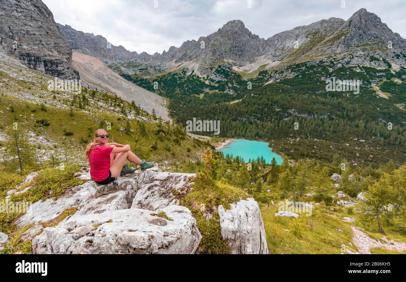 Jeune femme, randonneur assis sur des rochers et regardant le lac turquoise de Sorapeiss et le paysage de montagne, Dolomites, Belluno, Italie Banque D'Images