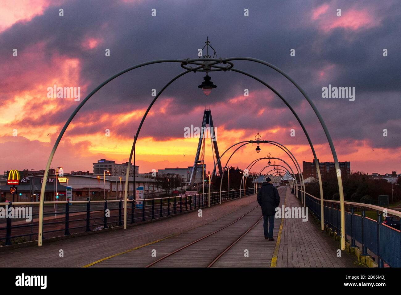 Lever du soleil à Southport, Merseyside. Fév 2020. Météo au Royaume-Uni ; ciel rouge flamboyant le matin, avertissement du système de tempête du marin. Lever du soleil et ciel orange au-dessus des randonneurs sur la jetée de Southport à l'aube. Banque D'Images