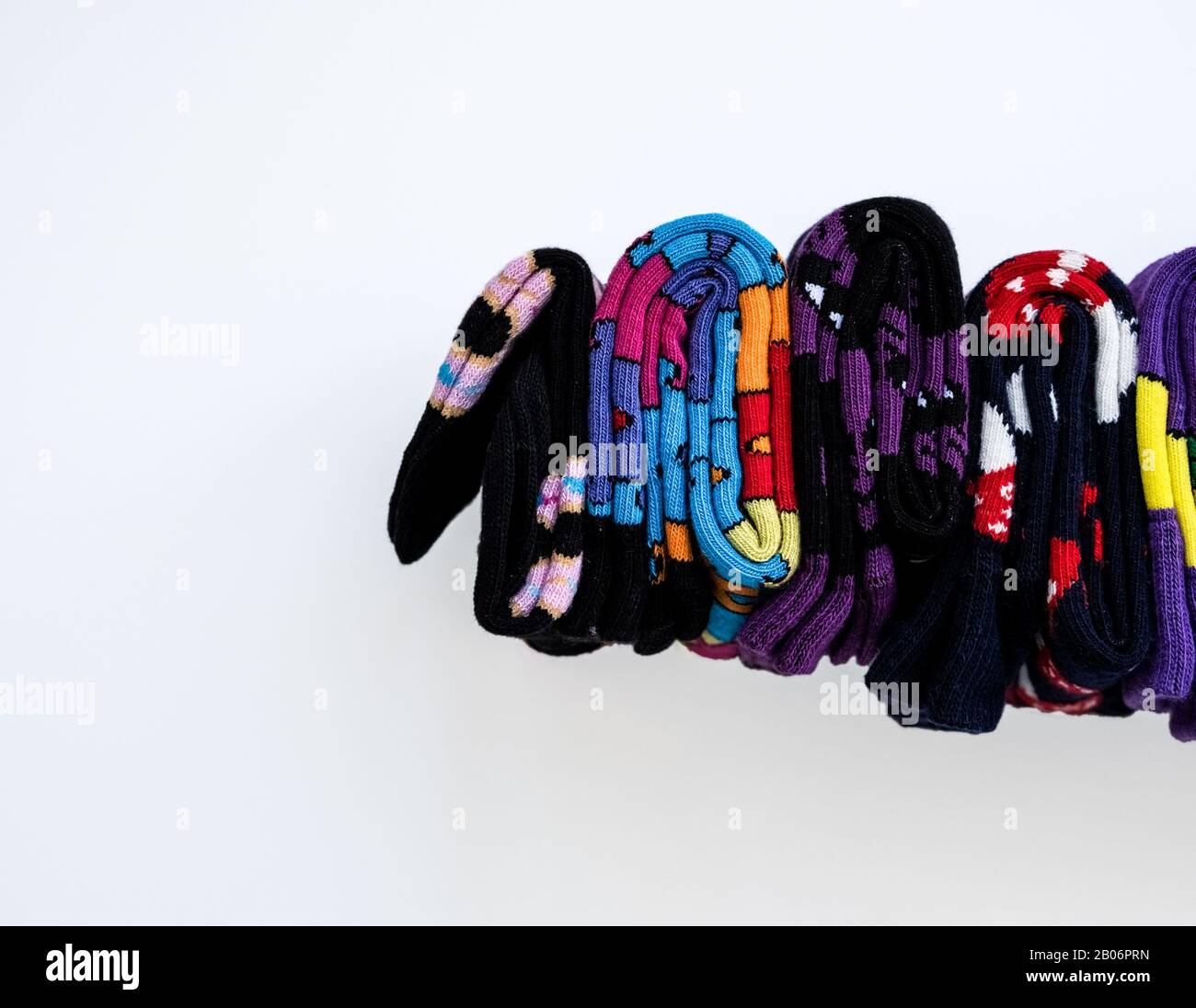 Plusieurs chaussettes en coton colorées roulent sur fond blanc. Banque D'Images