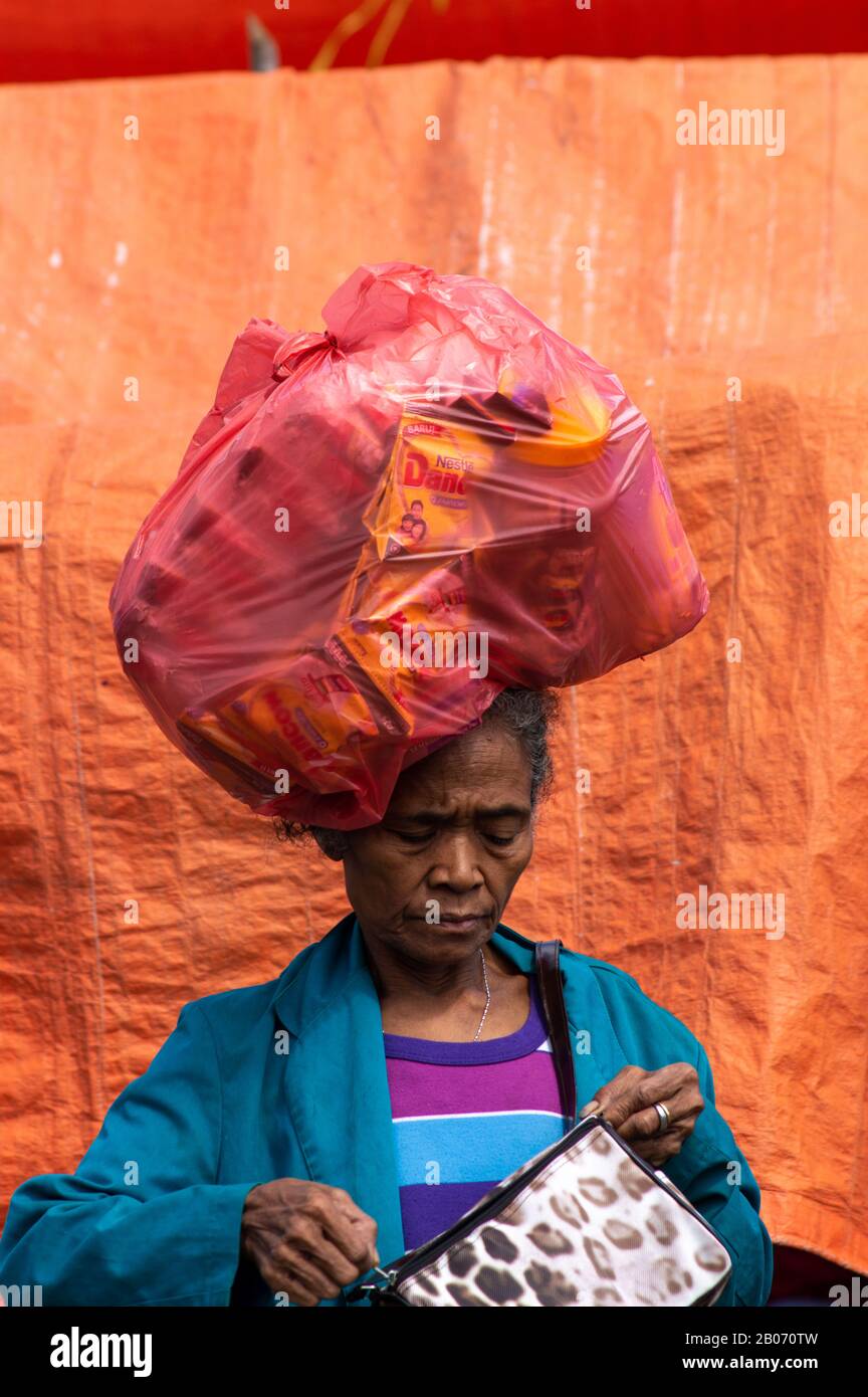 Une femme indonésienne âgée porte un gros sac sur la tête, de East Nusa Tenggara, Flores. Banque D'Images