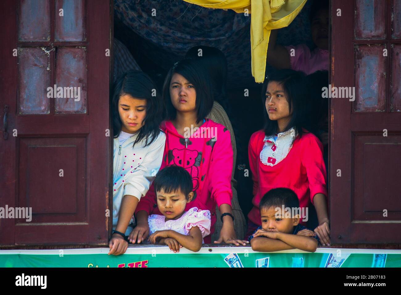 Une fille suit de la fenêtre de leur péniche, la régate de la pagode Phaung Daw O, le festival à Inle Lake. Banque D'Images
