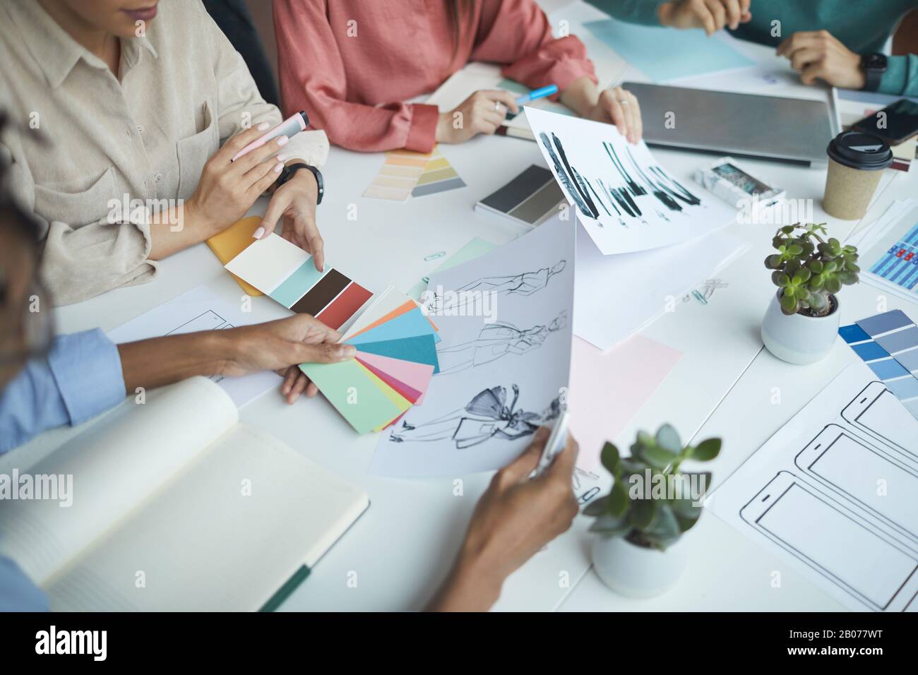 Gros plan d'un groupe de concepteurs assis à la table avec une palette de couleurs et des esquisses et discutant de la nouvelle collection Banque D'Images