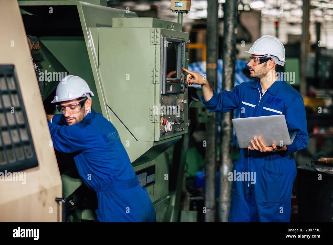 L'équipe d'entretien de la machine vérifie la CNC et reprogramme le processus pendant la production en usine. Banque D'Images