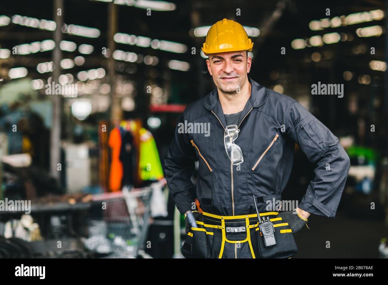 Heureux travailleur, portrait sourire beau travail avec des outils de sécurité ceinture et radio service homme en usine. Banque D'Images