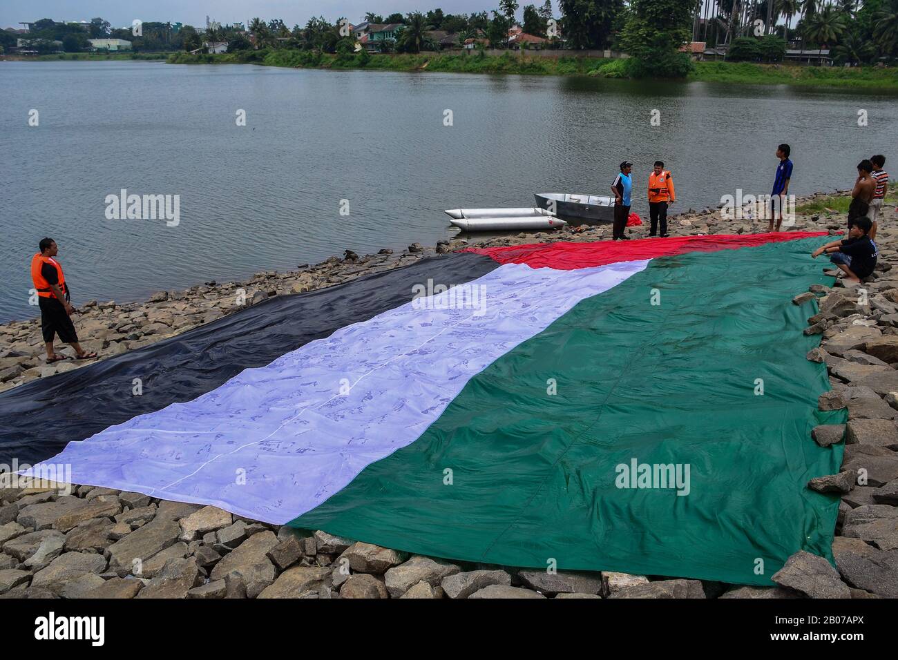 Tangerang, Indonésie - 23 février 2013 : les hommes indonésiens se lavent et sèchent le drapeau géant palestinien au bord de la rivière à Tangerang, Indonésie Banque D'Images