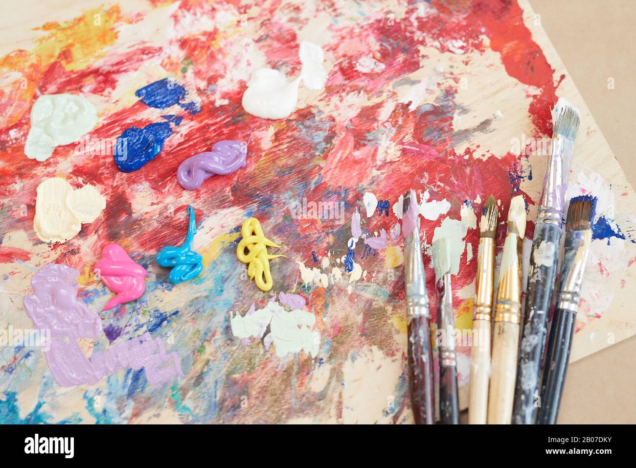 Gros plan de la palette avec peintures et différents pinceaux sur la table en atelier Banque D'Images