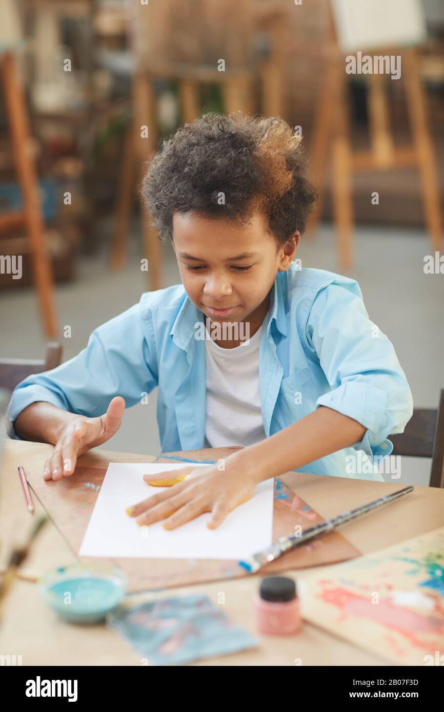 Petit garçon africain assis à la table et faire un artisanal avec des peintures au studio d'art Banque D'Images