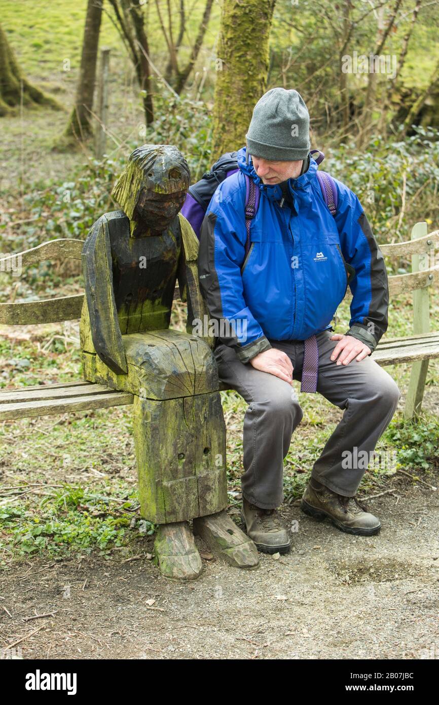 Walker s'est assis en regardant une sculpture rustique en bois d'une femme sur la piste Tarka à l'extérieur de Great Torrington, Devon, Angleterre Banque D'Images