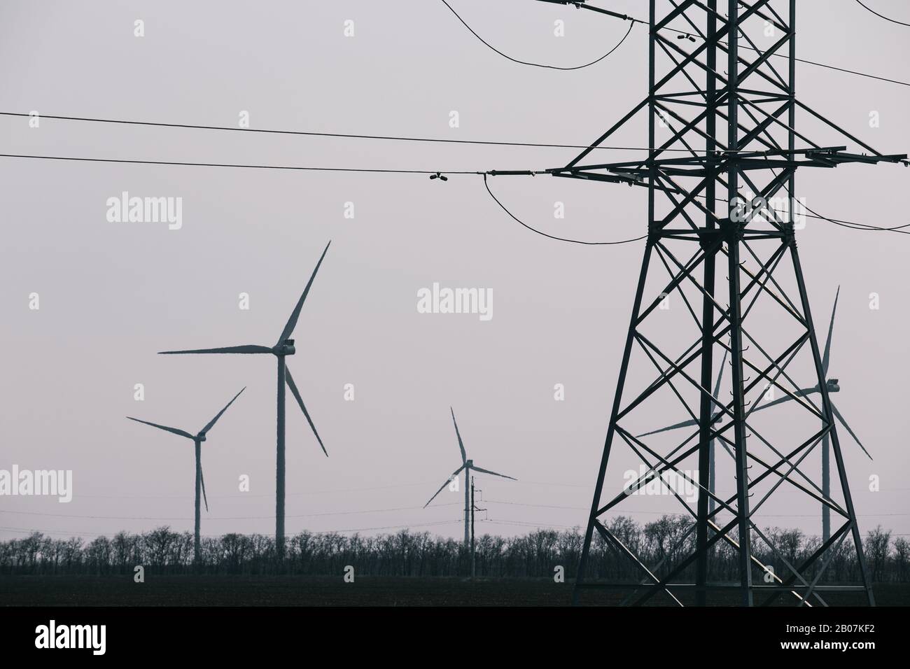 Pylon de transmission de l'électricité et éolienne du ciel gris en arrière-plan Banque D'Images