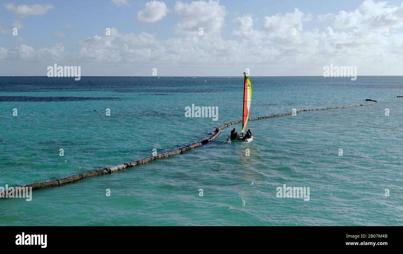 La famille navigue un petit catamaran sur les plages de Punta Cana en République Dominicaine, perspective aérienne des sports nautiques et de l'amusement en plein air dans les Caraïbes Banque D'Images