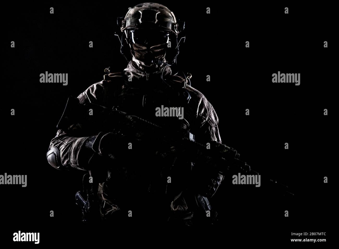 Les opérations spéciales de l'armée obligent un soldat en uniforme de masque et de combat, un canon de sous-machine armé, un portrait de studio bas-clé en noir, un tir en contour d'espace publicitaire Banque D'Images