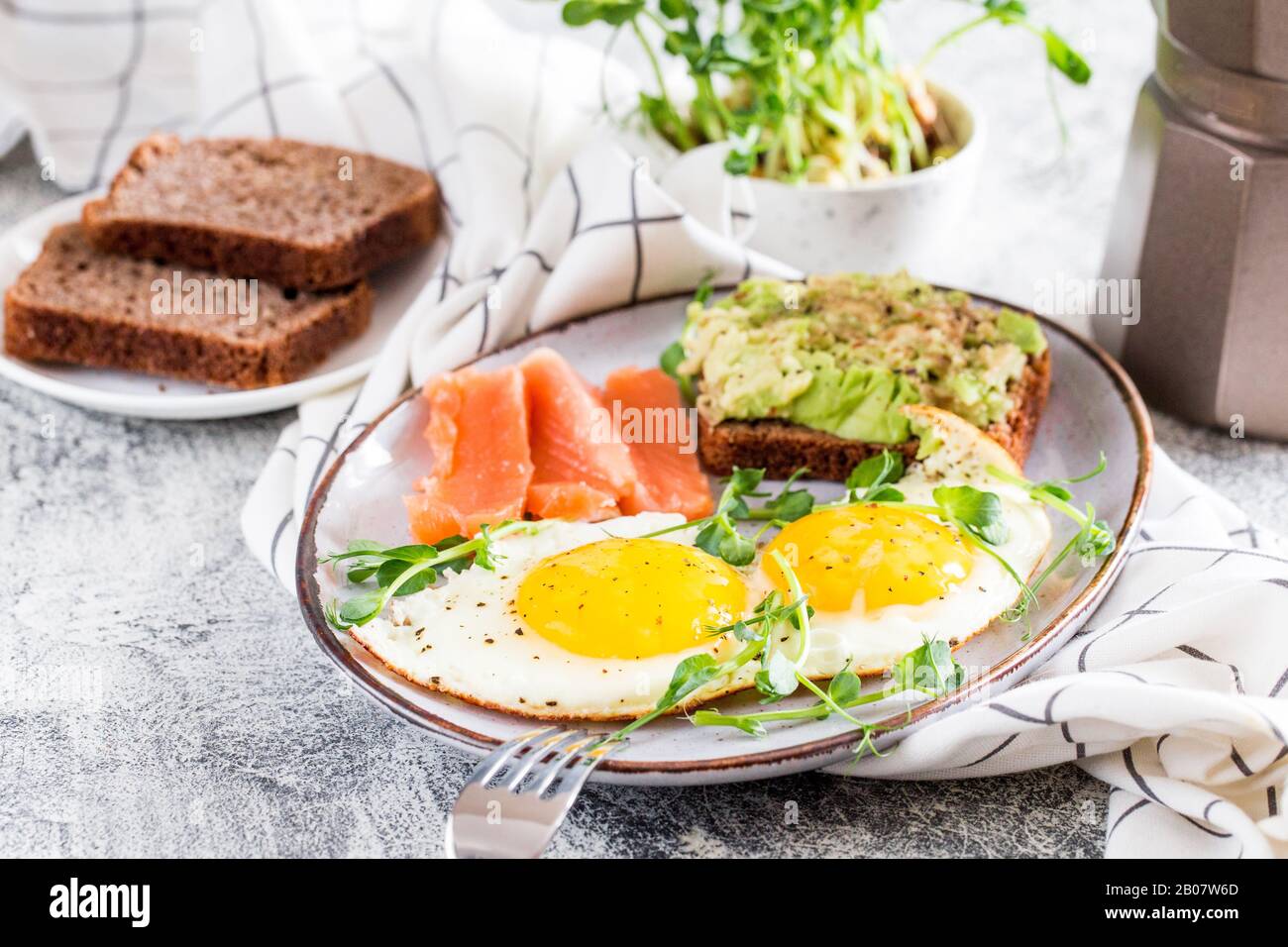 Petit-déjeuner aux œufs. Petit déjeuner sain et nutritif avec œufs, saumon, sandwich à l'avocat et graines de pois dénoyés. Banque D'Images