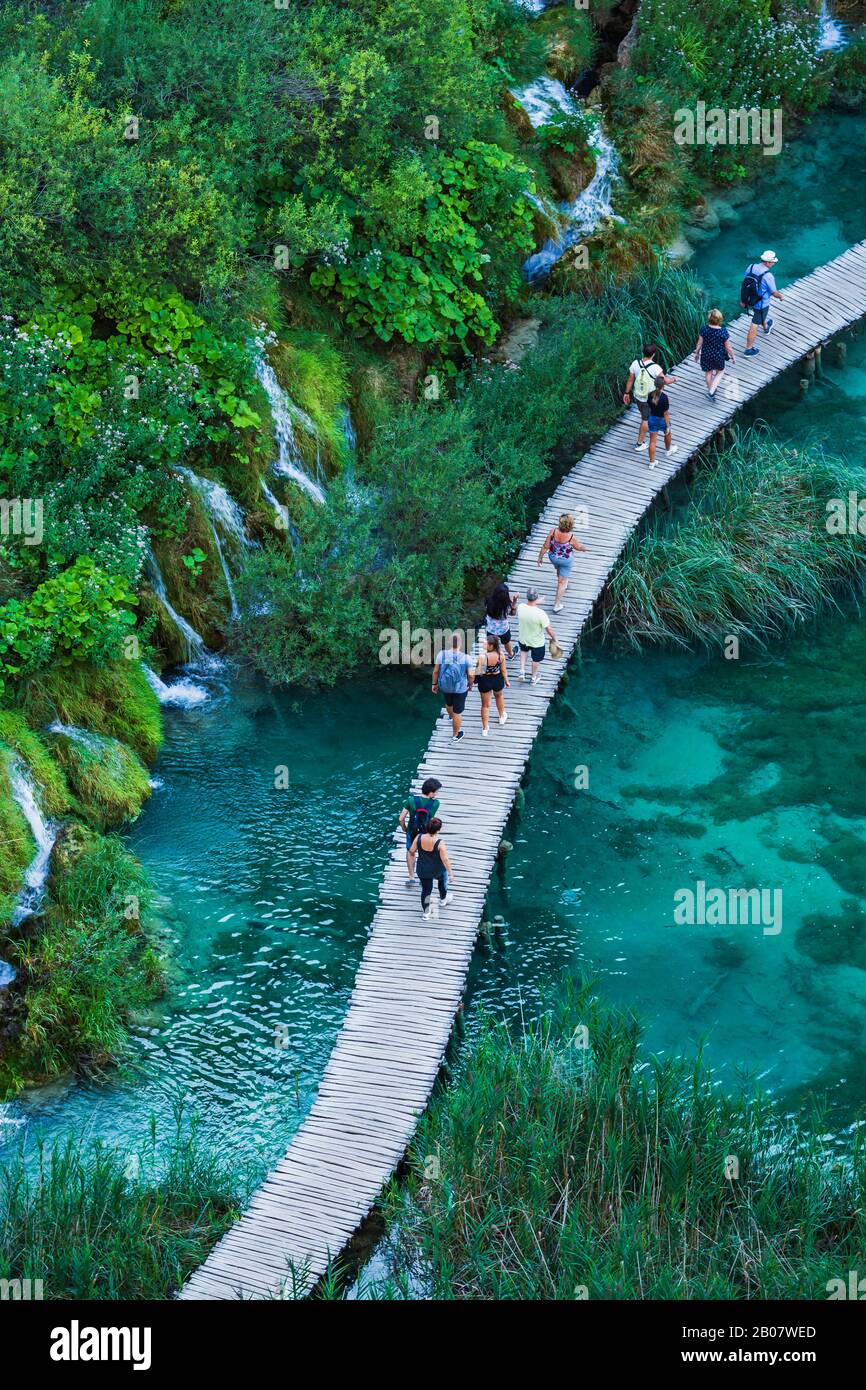 Les touristes marchent sur le chemin du bois, dans le parc national des lacs de Plitvice, site classé au patrimoine mondial de l'UNESCO. Banque D'Images