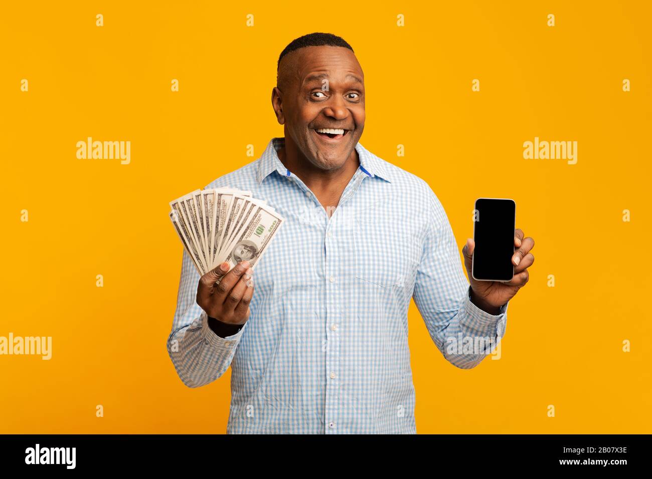 Homme africain mûr tenant beaucoup d'argent et de téléphone portable Banque D'Images