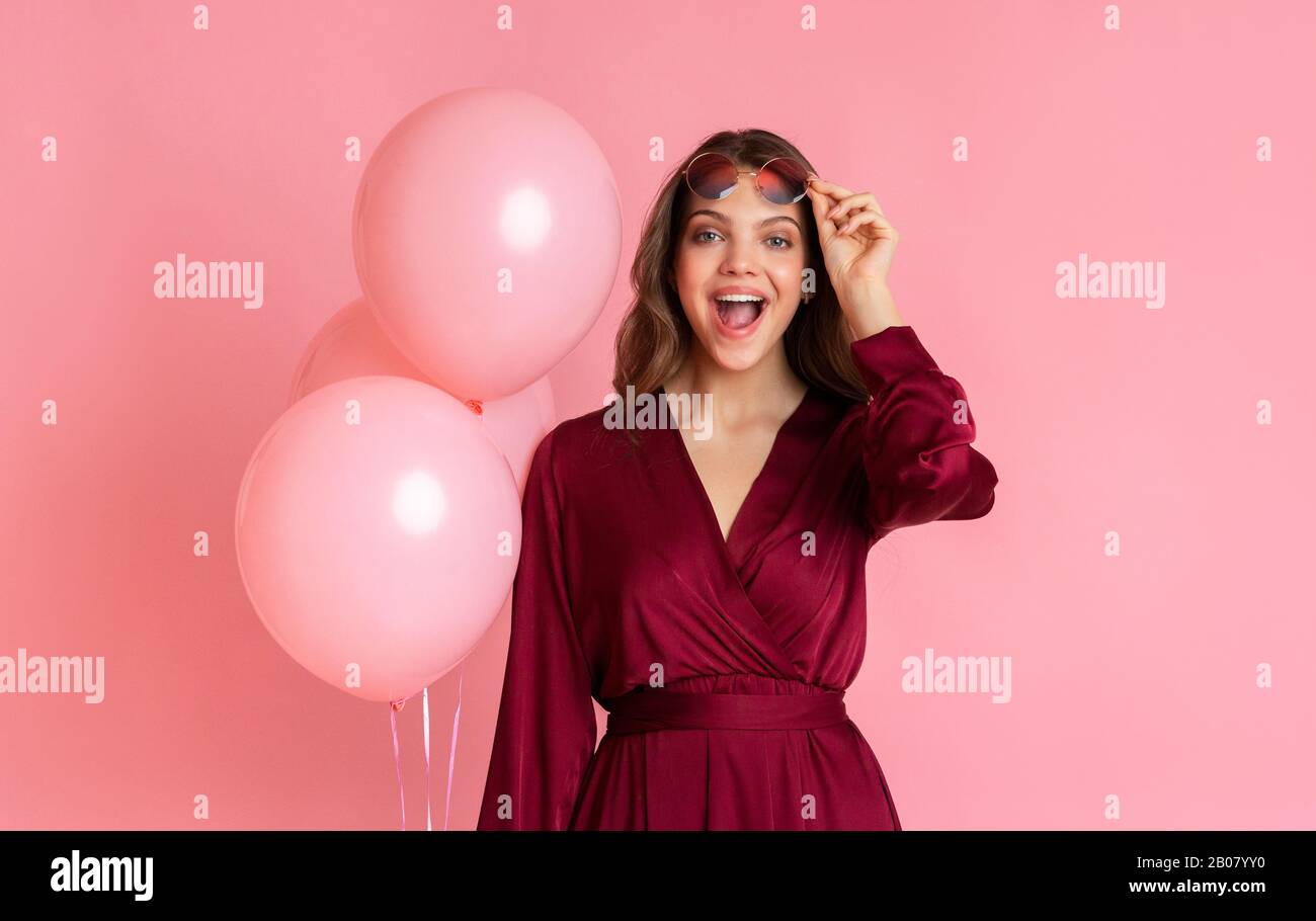 Génial. Surprise Girl Holding Des Ballons Roses Et Ouverture De La Bouche Dans L'Étonnement Banque D'Images