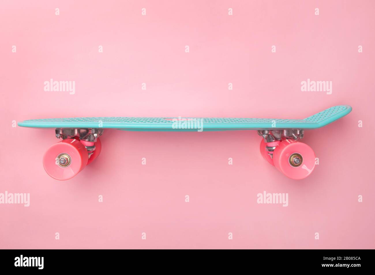Vue latérale du skateboard Penny board sur fond rose. Mini-croiseur. Banque D'Images