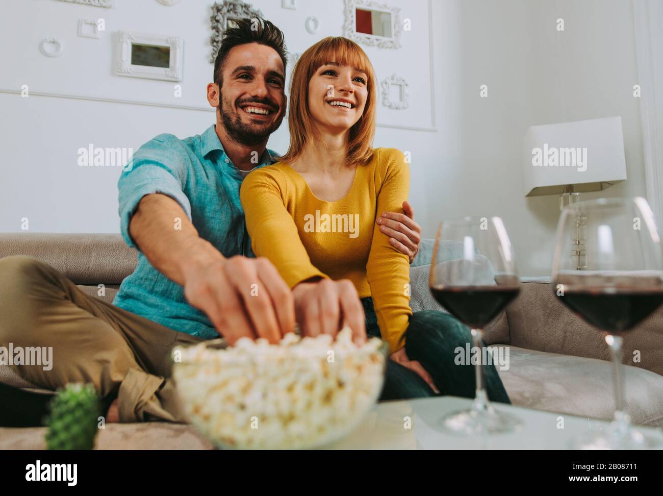 Les jeunes couples passent du temps ensemble à la maison. Homme et femme assis sur le canapé et s'amuser Banque D'Images