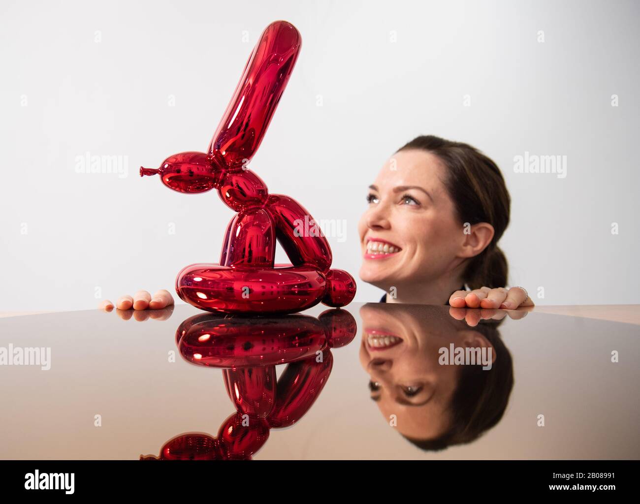 Un visiteur vues 'Balloon Rabbit (rouge), par Jeff Kons, une partie de l'exposition 'XXI' de l'exposition des œuvres non vues et rares par des tels que RETNA, Damien Hirst et Condo, Qui accompagne le lancement de l'ARTCELS, une plate-forme numérique pour les investissements d'art à puce bleue à la Maison des Beaux-Arts - HAFA Gallery à Londres jusqu'au 5 mars. Banque D'Images