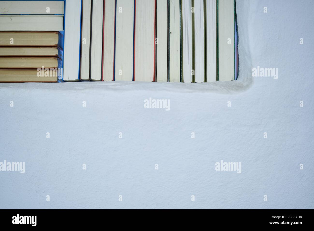 Détail d'un assortiment de livres dans un mur blanc texturé avec espace de copie, dos de livres dans une maison de campagne Banque D'Images