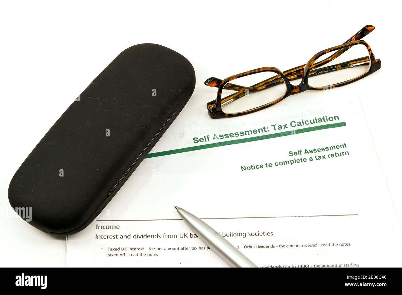 Vue rapprochée d'un formulaire de déclaration de revenus d'auto-évaluation avec un stylo, une paire de lunettes et un étui de lunettes sur fond blanc Uni Banque D'Images