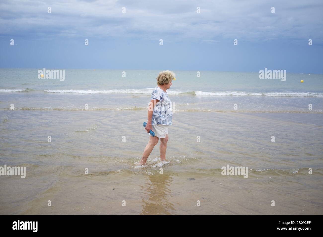 Femme marchant sur la plage, pieds nus en mer Banque D'Images