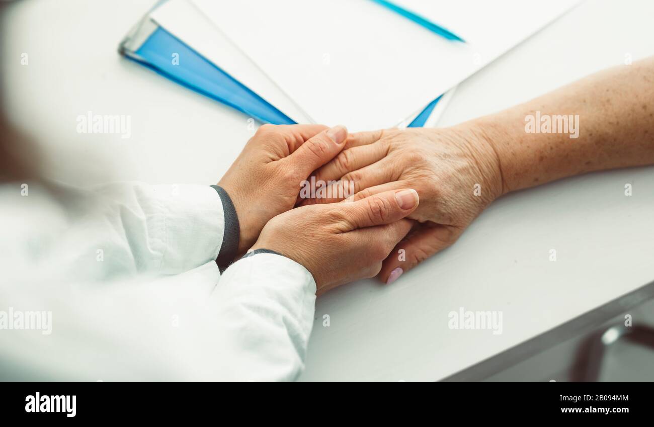 Le médecin tient la main d'une femme âgée. Une infirmière prend en charge une patiente âgée. Banque D'Images