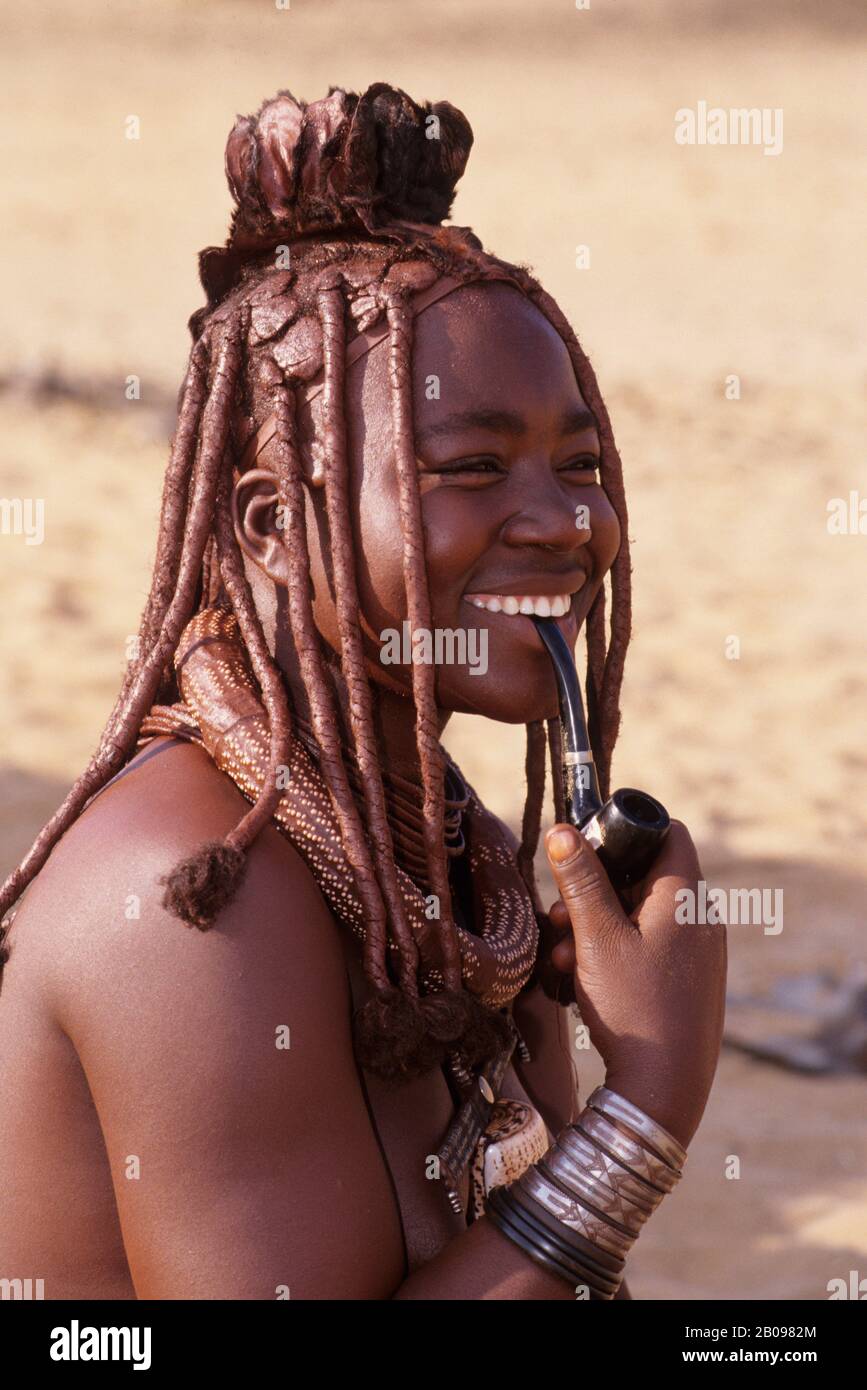 NAMIBIE, SKELETON COAST, HARTMANN VALLEY, NOMADE HIMBA PEOPLE CAMP, HIMBA FEMME AVEC PIPE Banque D'Images