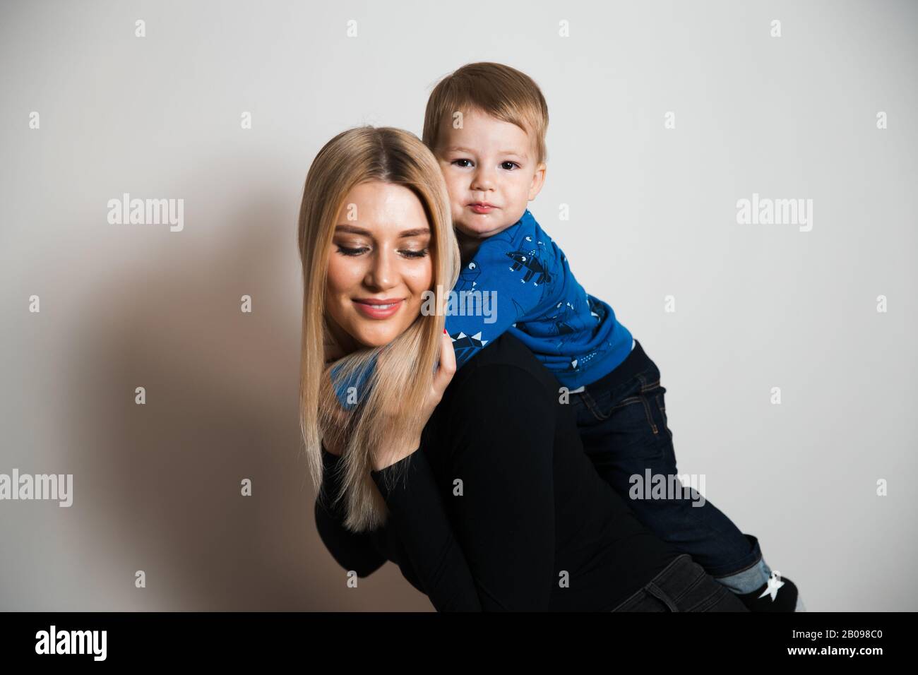 Blonde cheveux longs chaud glamour mère jouant avec son enfant de bébé à la maison passer des valeurs de qualité famille temps Banque D'Images