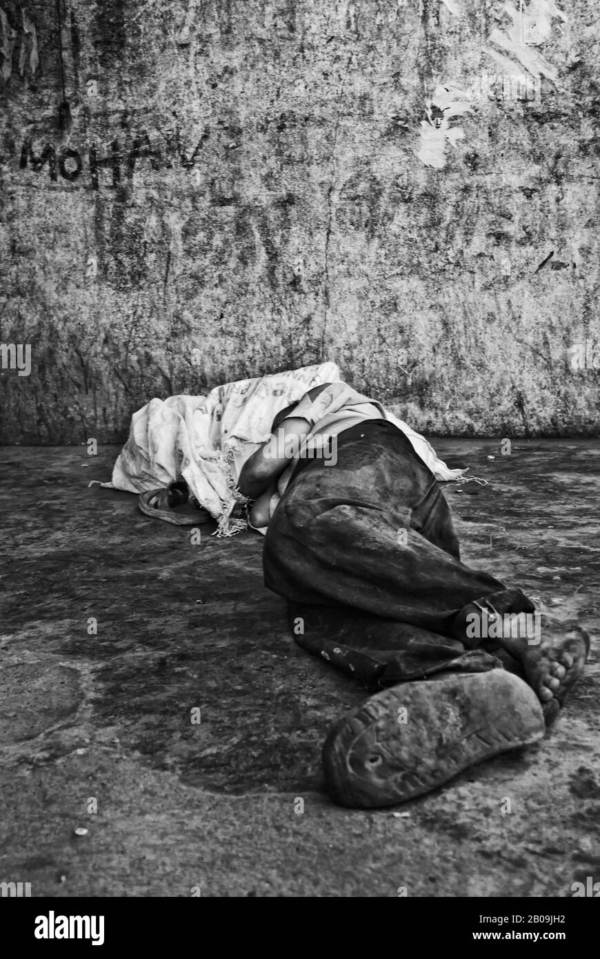 Un homme dort sur le pavé à Shivajinagar bus Terminus, à Bangalore. La plupart des personnes démunies sont prises en charge par les gares ferroviaire et routière et envoyées aux maisons des débutants dans les villes. Bangalore, Karnataka, Inde. 27 Décembre 2010. Une des images de l'histoire de la photo, Criminalisant la pauvreté, par Ayush Ranka. Banque D'Images