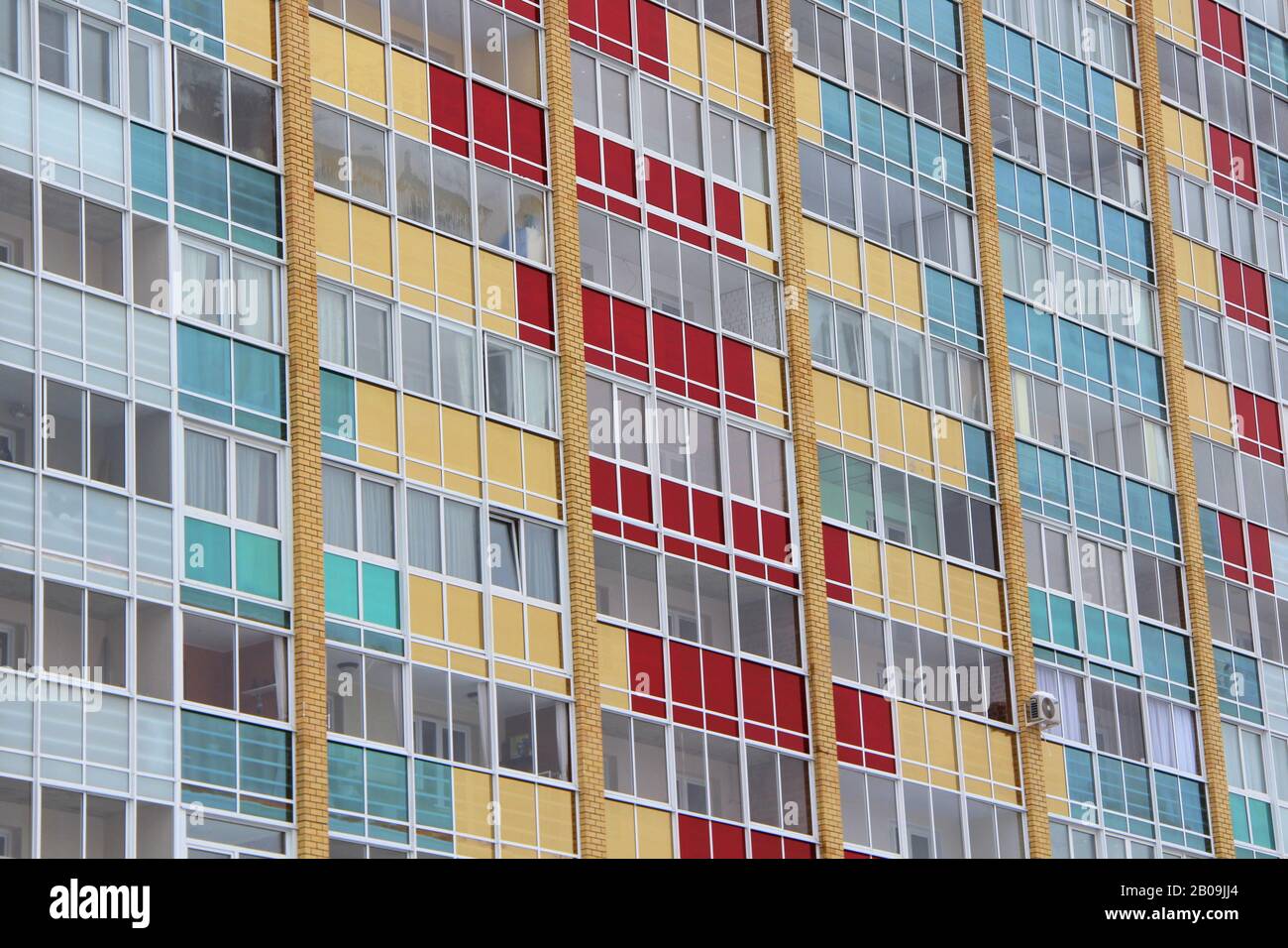 Mur d'une maison moderne en briques carrelées avec des rangées de fenêtres et des vitraux multicolores. Stocker la photo pour le Web, l'impression, l'arrière-plan et le fond d'écran, avec un espace vide pour le texte Banque D'Images