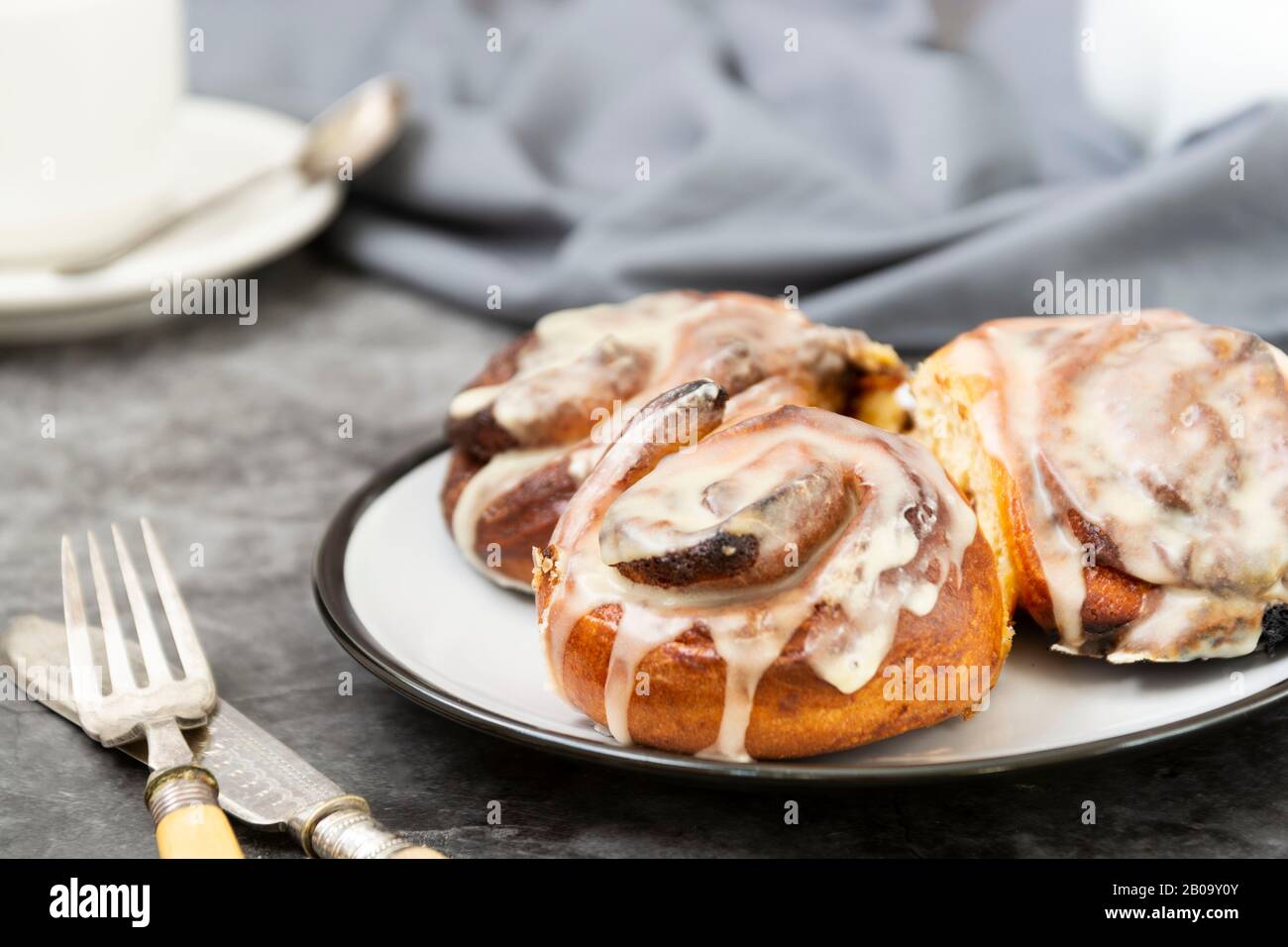 Pain ou cinaons danois à la cannelle sur fond sombre avec tasse à café. Pâte maison douce. Banque D'Images