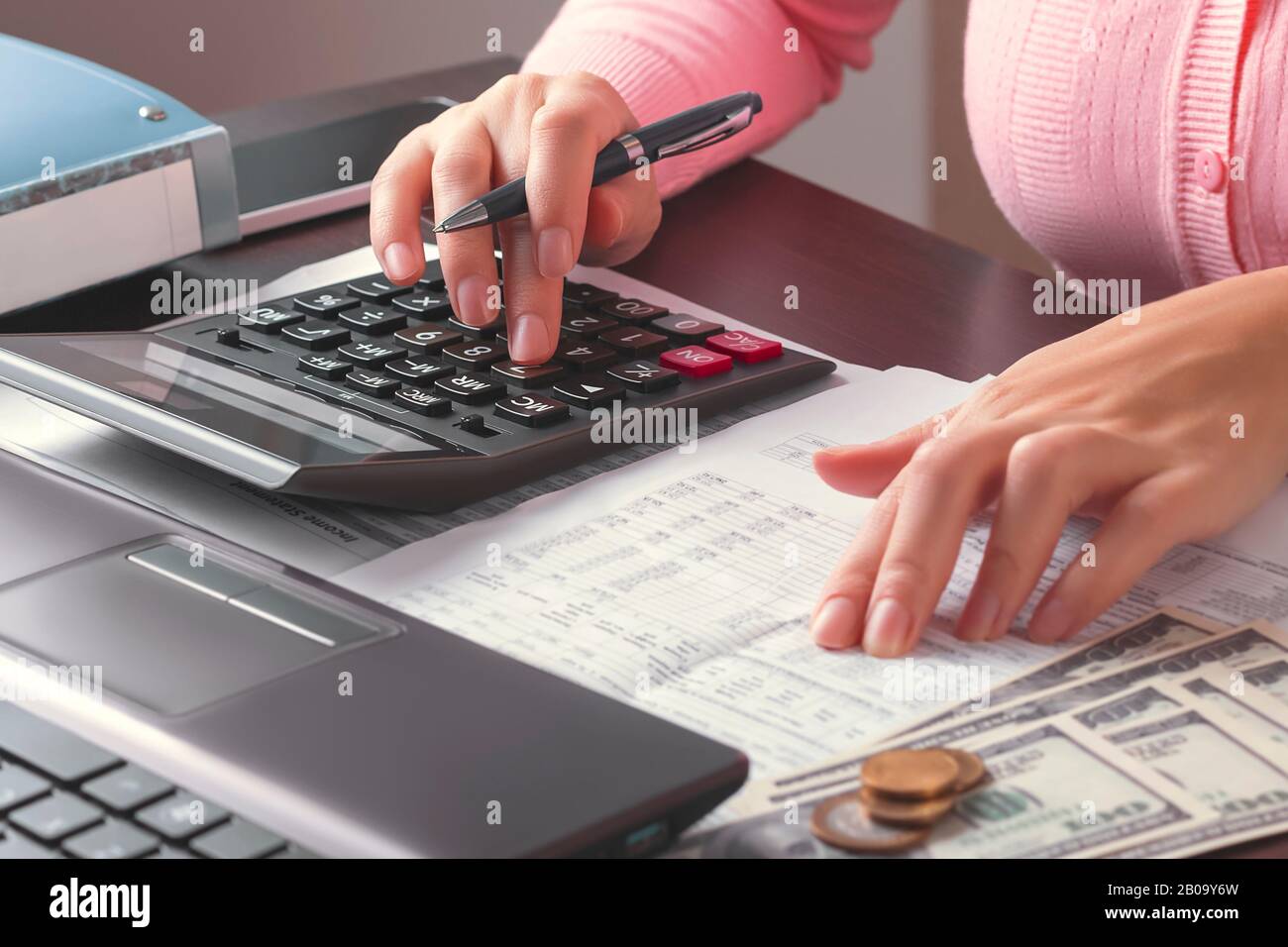 Business woman à la recherche des données nécessaires dans un tableau d'un document et les calcule sur une calculatrice. Le concept de calcul des taxes et des paiements Banque D'Images