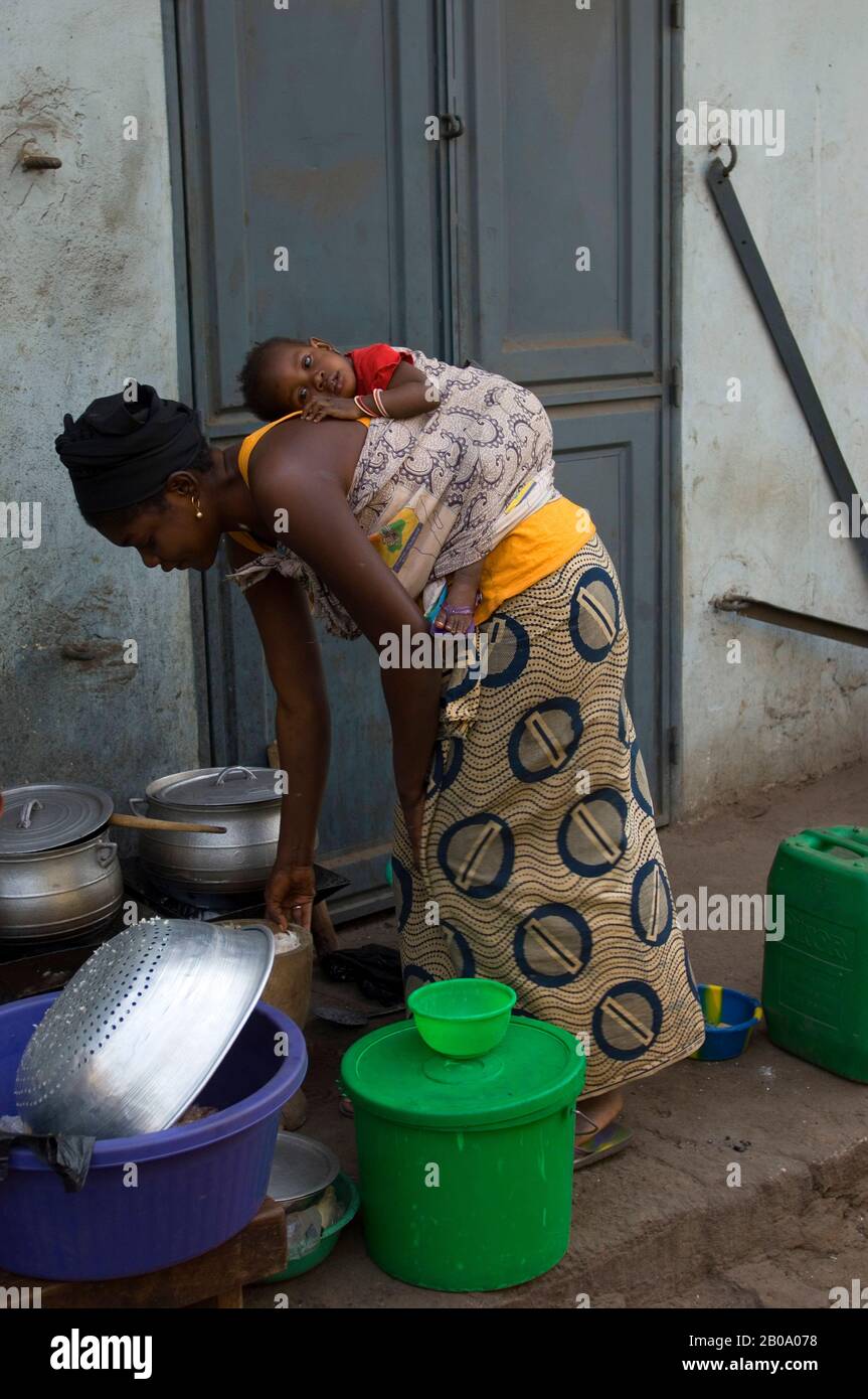 MALI, BAMAKO, SCÈNE DE RUE, MÈRE AVEC CHOLD VAISSELLE DE LAVAGE Banque D'Images