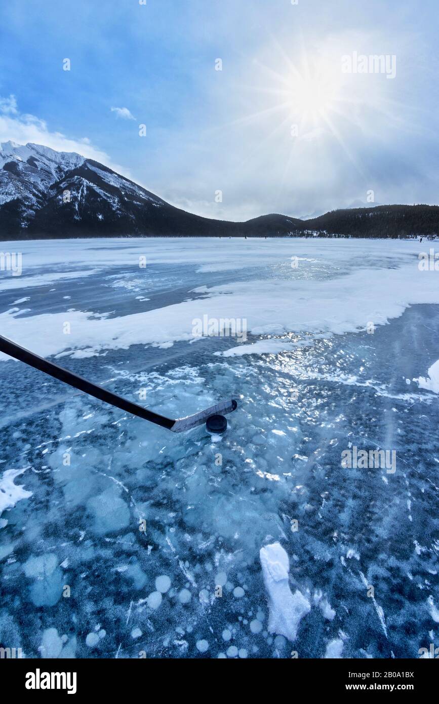 Jouer au hockey sur glace sur le lac gelé Minnewanka dans les Rocheuses canadiennes du parc national Banff, Alberta, Canada. Crosse de hockey et palet avec gel visible Banque D'Images