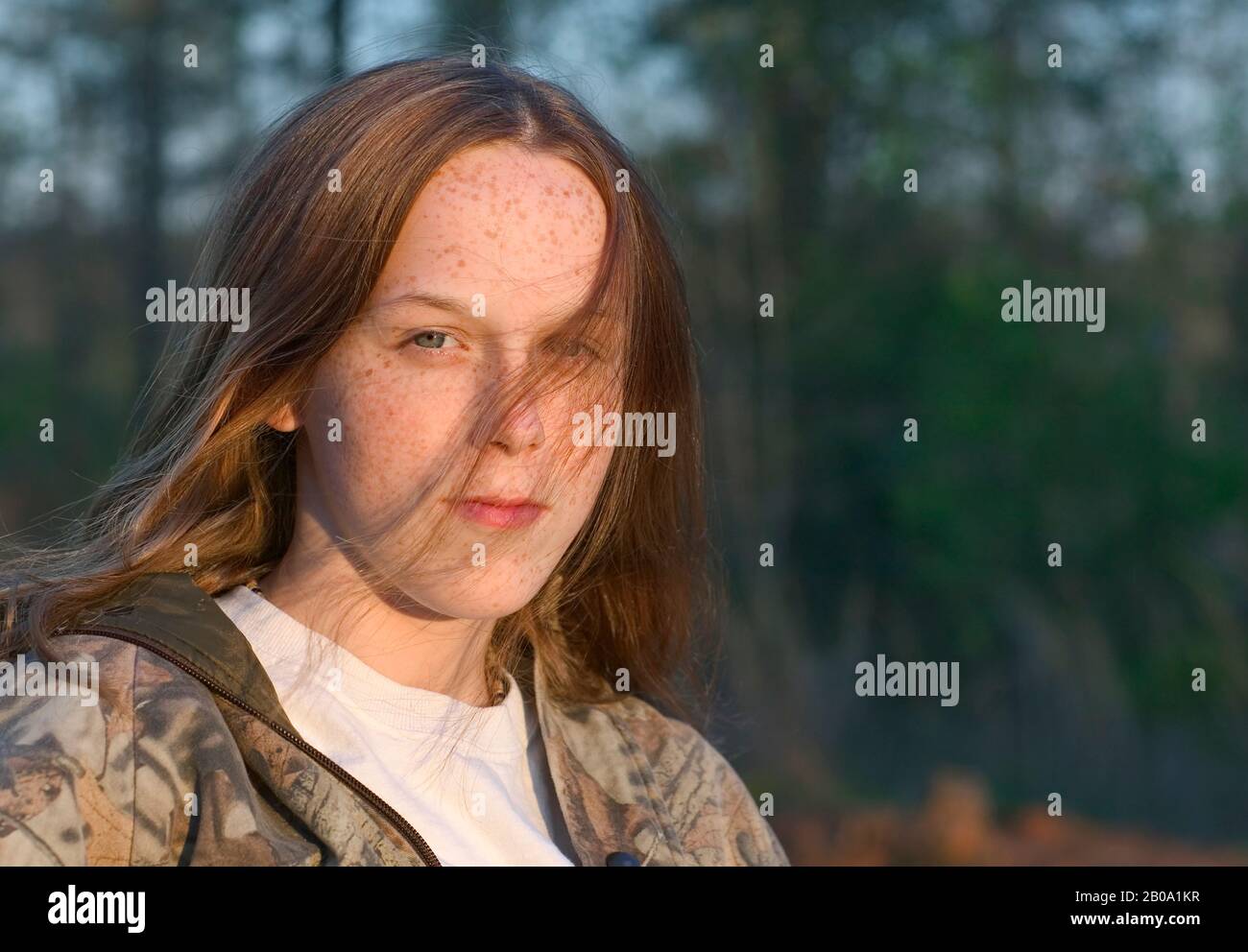 Une jolie jeune fille de 12 ans, aux yeux bleus, aux cheveux rouges, à la peau et aux cornichons équitables, portant un tee-shirt blanc et une veste camouflage ouverte. Headshot. Eng Banque D'Images