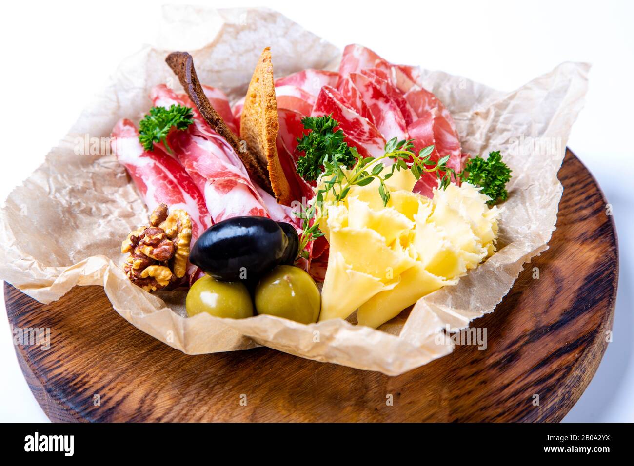 Ensemble de vins : cou sec, fromage, olives et crackers de seigle. Seth est allongé sur du papier parchemin froissé sur un plateau rond en bois Sur fond blanc. Banque D'Images