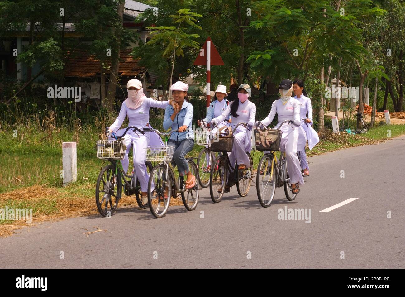 VIETNAM, PRÈS DE DA NANG, ÉCOLIÈRES DANS AO DAI TRADITIONNEL (ROBE) SUR LES VÉLOS VENANT DE L'ÉCOLE Banque D'Images