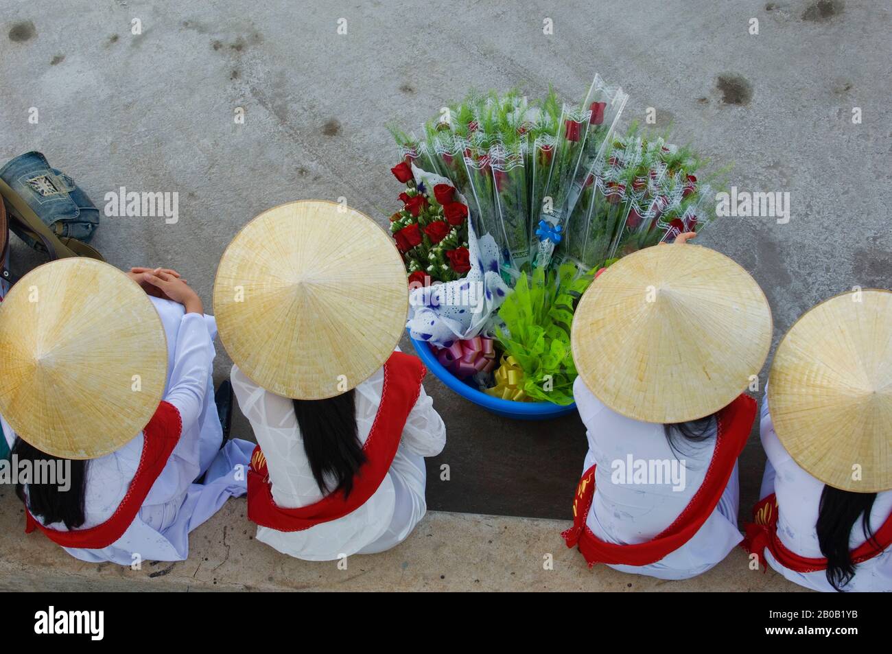 VIETNAM, QUI NHON, PORT, FEMMES EN ROBE TRADITIONNELLE (AO DAI) ET CHAPEAUX DE CÔNE (NON LA) ASSIS ET EN ATTENTE D'ACCUEIL DES TOURISTES Banque D'Images